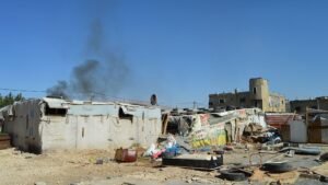Smoke rises over rows of UNHCR tents in the settlement. More than 220,000 Syrians still live in informal camps scattered across the region, many surviving without formal infrastructure or waste services.